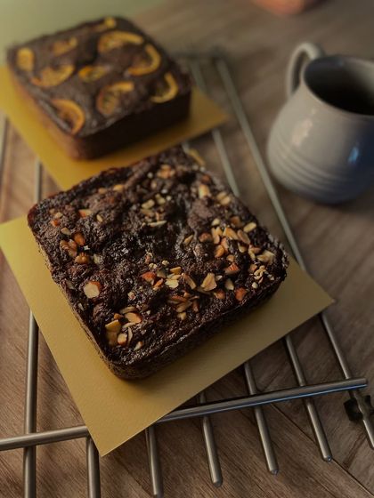 A different view of the two chocolate cakes, highlighting the contrast between the nutty topping and the candied orange slices.