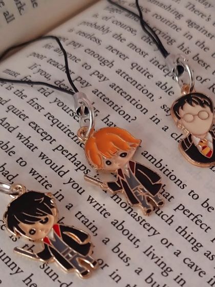A close-up of the Harry, Ron, and another wizard character charm, showing the detailed enamel work.