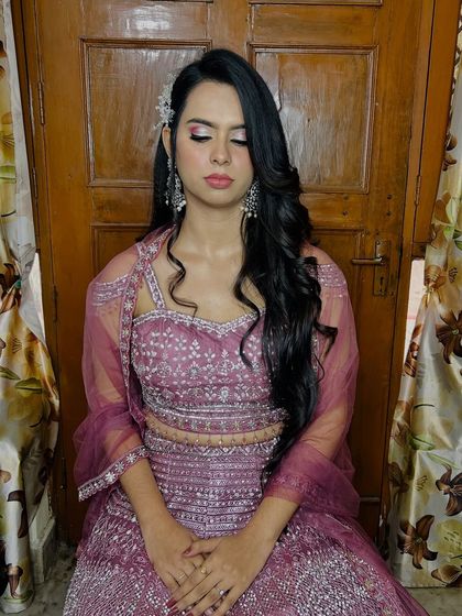A full-length seated portrait, showing the entire mauve lehenga.