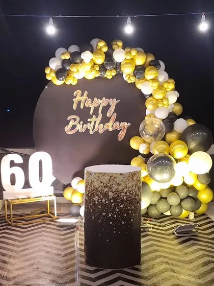 This wide shot shows the complete 60th birthday backdrop on a terrace, with overhead lighting enhancing the celebratory mood. The chevron-patterned floor runner adds another layer of style.