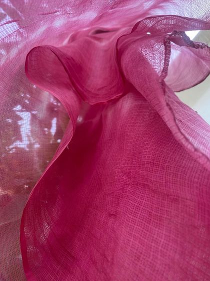 An abstract, close-up shot of the pink Kota silk stole, showing the delicate weave of the fabric and the intense color from the Sappanwood dye.