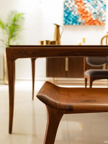 This dining set from Alankaram showcases exquisite craftsmanship. The elegantly curved legs of the bench and table are a beautiful example of contemporary Indian furniture design.