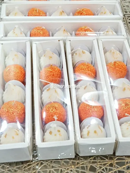 A close-up of my laddoo and modak candle gift sets, neatly packed and ready for dispatch. The clear packaging showcases the intricate details of each candle.