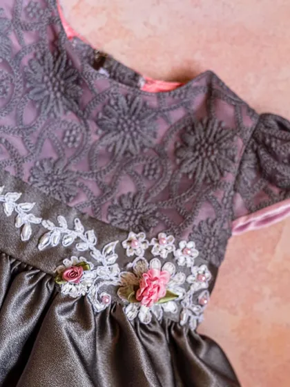I love the sophisticated combination of this grey satin dress with intricate floral embroidery. The pink and white ribbon flowers add a soft, delicate touch of color.
