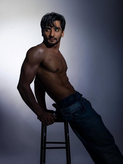 A powerful pose on a stool that combines strength and style. The dramatic lighting adds an edge.