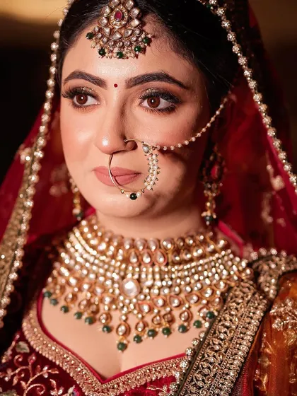 A close-up on the bride's face, showing the intricate details of her polki necklace and nath.