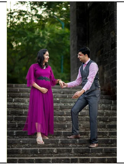 A classic, romantic pose on a grand staircase, with the dad-to-be gently leading his partner.