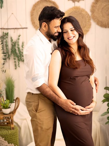 A loving embrace. This couple's portrait in the boho studio setup is all about connection, warmth, and the shared excitement of their pregnancy journey.
