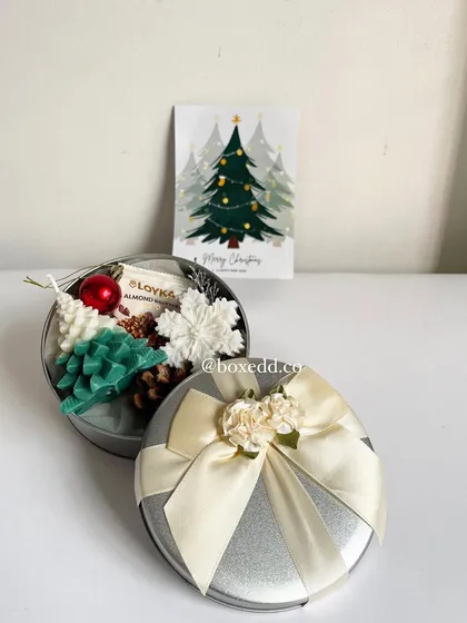 A perfect Secret Santa gift. This festive tin includes Christmas-tree-shaped candles, toffees, and a holiday card, all beautifully presented with a satin bow.