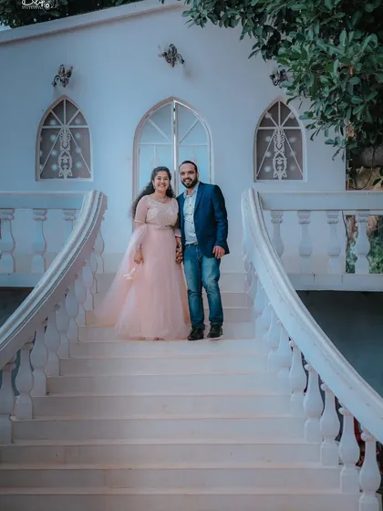 A classic pose on a sweeping white staircase. The couple's formal attire and the grand architecture make for a timeless and elegant pre-wedding photo.