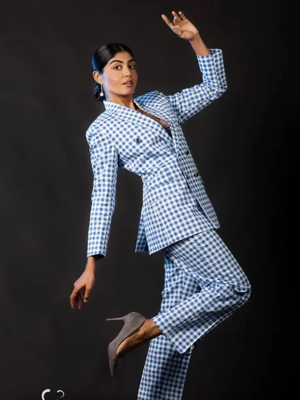 A playful, high-fashion pose that showcases the full suit. The dynamic movement creates a sense of fun and energy.