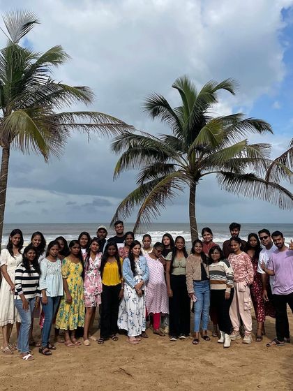 A group photo on the beach with palm trees in the background.