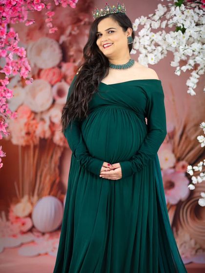 A stunning portrait against a floral backdrop. The deep green gown and jeweled crown create a look of natural elegance and sophistication.