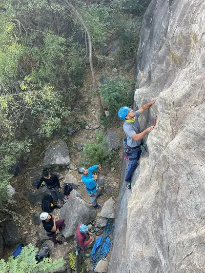 A top down view of a climber leading a route at Varlakonda, with the group gathered at the base.