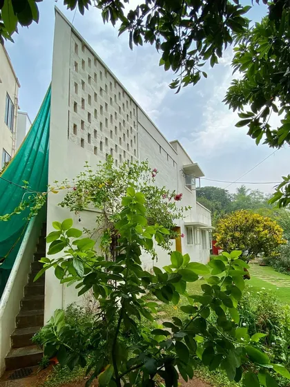 The 'Wedge Home' in Hyderabad, built 23 years ago on an unconventional triangular plot. The design uses a distinctive perforated wall to create privacy and filter light, turning the site's challenges into a unique architectural feature.