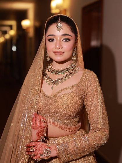 A close-up portrait of a bride in our golden lehenga. The sheer dupatta and layered necklace add to the overall grace and sophistication of the look.