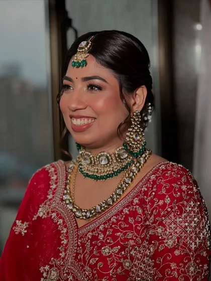 A classic Indian bride in red, looking absolutely timeless. I focused on creating that signature glass skin finish to make her complexion luminous, paired with a warm, earthy lipstick and defined eyes to make her smile the center of attention.