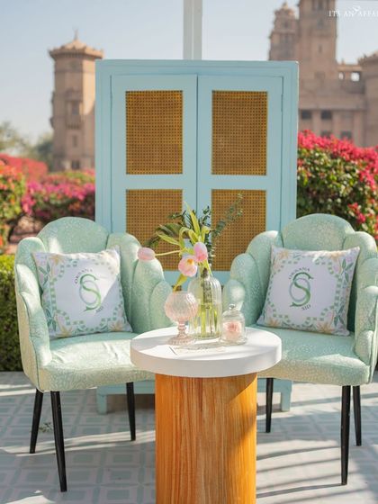 A charming seating vignette with custom monogrammed cushions, set against the backdrop of the Umaid Bhawan Palace.