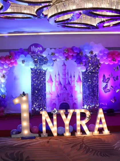 A full view of Nyra's princess-themed first birthday stage, showcasing the grand scale and beautiful purple lighting.