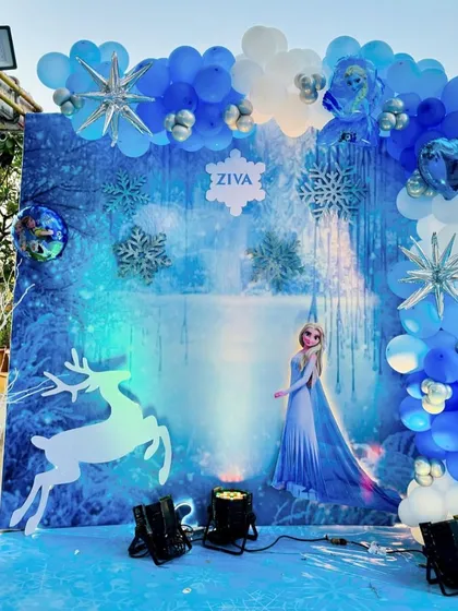 A winter wonderland comes to life with this Frozen-themed backdrop. Featuring Elsa against an icy landscape and surrounded by a blue and white balloon arch, it's the perfect spot for birthday photos.