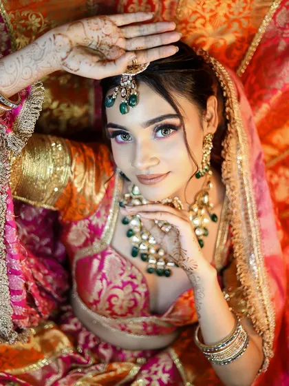 An artistic overhead shot featuring beautiful henna designs. The makeup is soft and romantic, perfectly complementing the traditional pre-wedding elements.