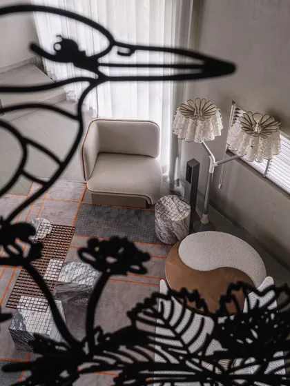 A creative perspective shot through the metal railing, looking down into the living area. The bird silhouette frames the scene below, adding a layer of artistic storytelling to the home's interior design.