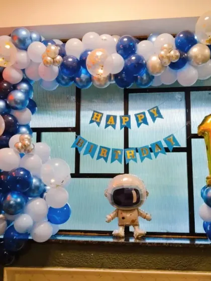 A simple yet effective astronaut-themed window decoration for a first birthday, using a balloon garland and character foil.