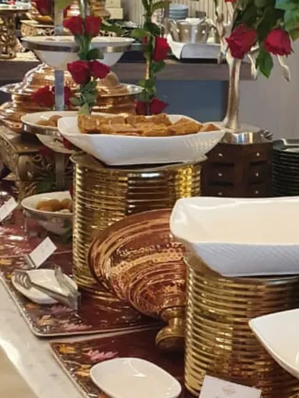 Another view of the red rose and copper buffet. This angle shows the tiered serving platters and the abundance of food, promising a feast for the senses.