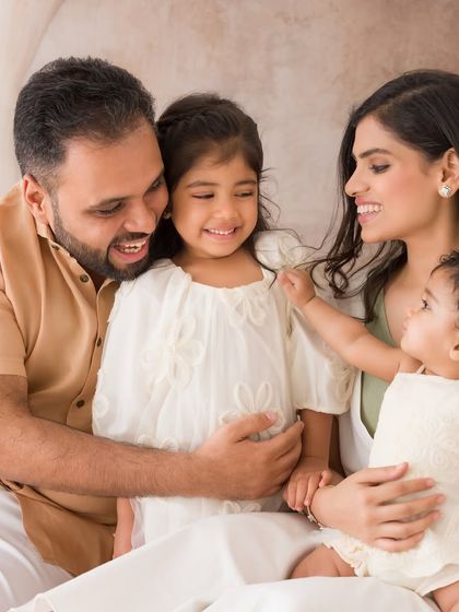 A beautiful family portrait filled with gentle interactions. The parents and daughters share loving gazes in this candid, emotional image.