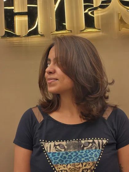 A profile shot of a client with a new hair color. The layered cut is styled away from the face to show off the subtle, natural-looking highlights.
