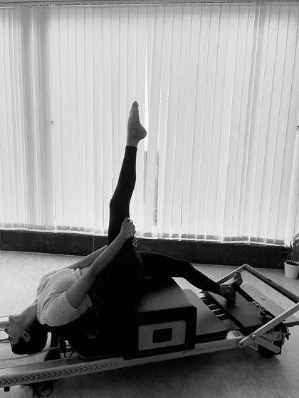 A deep hamstring stretch on the reformer. The machine's carriage allows for controlled movement to safely increase flexibility.