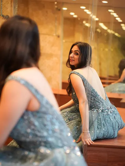 A mirror reflection shot in the grey gown, adding an artistic touch to the festive lookbook.