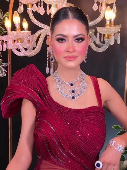 A close-up of a client in a magnificent red sculpted gown, paired with a sapphire and diamond necklace.