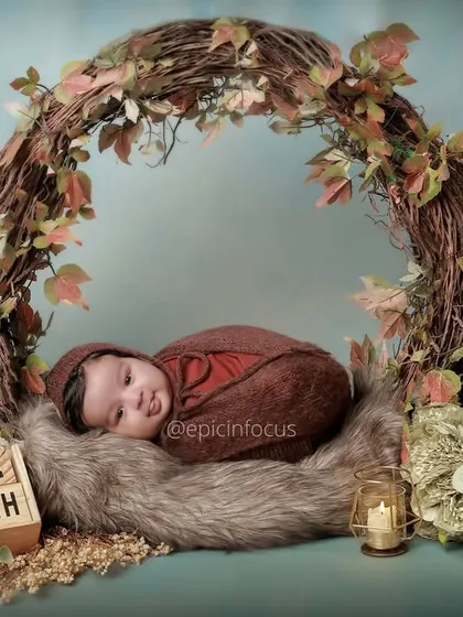 This two-month-old baby is nestled in a rustic, vine-covered wreath. We use natural elements and soft textures to create serene and artistic newborn portraits.