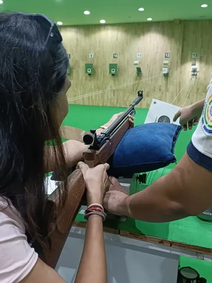 We provide hands-on instruction. A coach is helping a participant adjust her grip and aim, demonstrating our commitment to personalized guidance for every person who walks through our doors.