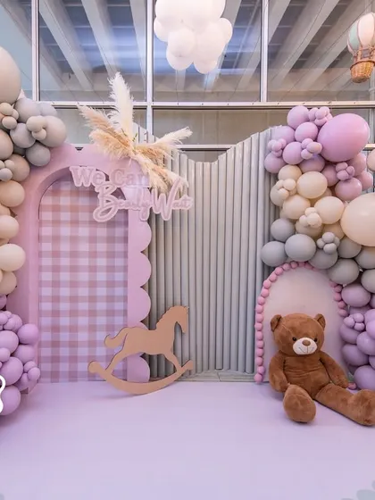 The main photo backdrop for the teddy bear baby shower, combining soft pastel balloons, a rocking horse, and a gingham arch to create a sweet and welcoming focal point.