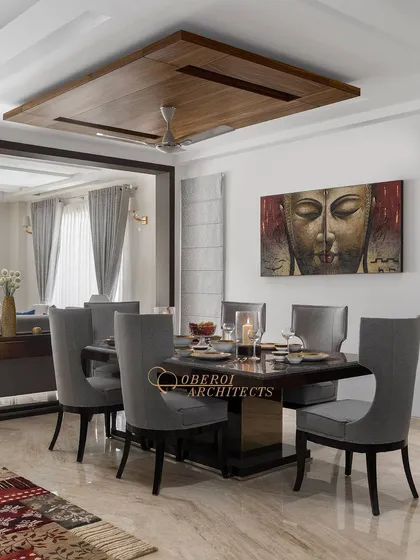 An elegant dining room featuring a dark wood table, grey upholstered chairs, and a large Buddha artwork that adds a sense of tranquility.