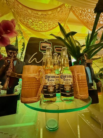 A detailed shot of the decor at our rustic whiskey station, featuring Corona beers, wooden mugs, and a saxophonist statue.