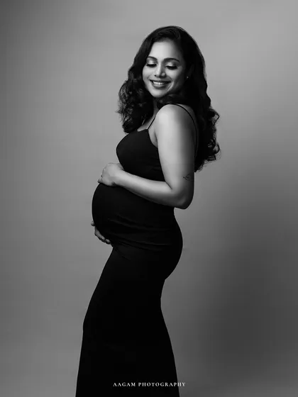 A joyful and candid-feeling black and white maternity portrait. Her smile is radiant, and the simple black dress is classic and chic.