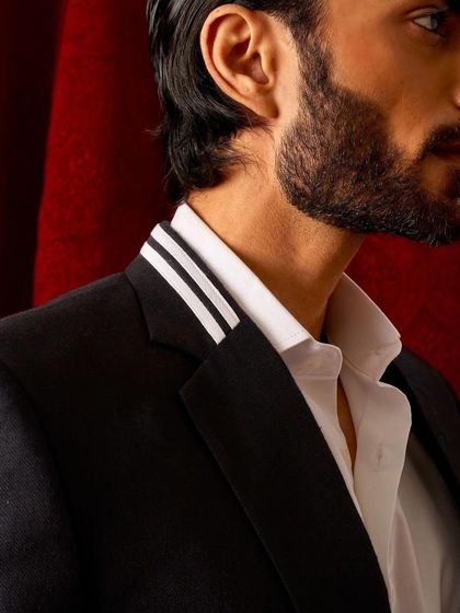 A close-up on the collar detail of the striped black blazer, showing the precision of the tailoring.