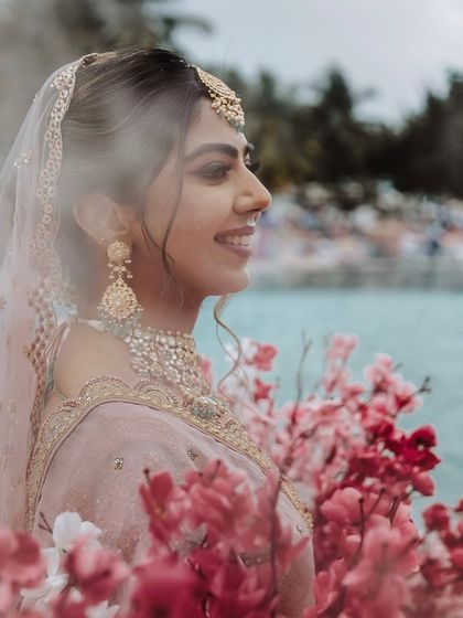 A dreamy shot of Mahima surrounded by flowers. Her makeup, with its soft pink tones and defined liner, enhances her natural beauty.