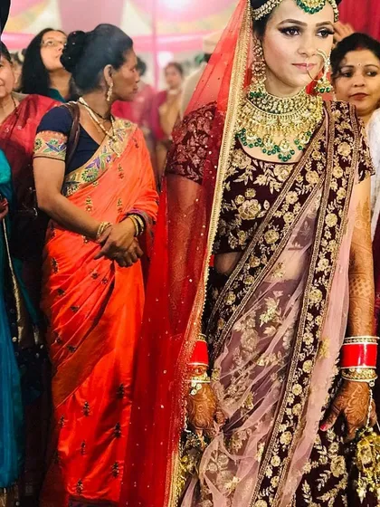 A beautiful bride on her wedding day, wearing a deep maroon velvet lehenga with intricate gold embroidery. This complete bridal look, including the double dupatta, is available for rent.