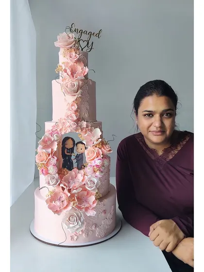Your love story, immortalized in cake. This grand engagement cake features a recreation of the proposal scene, complete with personalized, handcrafted figurines of the couple, all framed by a cascade of handmade sugar flowers.