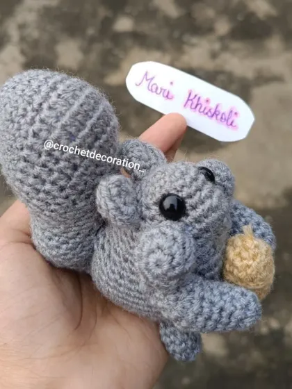 This is our 'Mari Khiskoli', a signature crochet squirrel that has become a customer favorite. Each one is handmade with soft grey yarn, featuring a bushy tail and a tiny acorn, making it a perfect, durable companion for imaginative play.