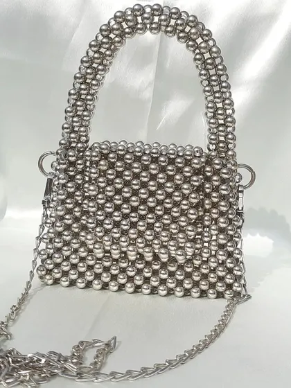 A clear, straight-on view of the silver beaded mini bag. This angle highlights the bag's boxy structure, the neatly woven beads, and the hardware for attaching the optional chain strap.