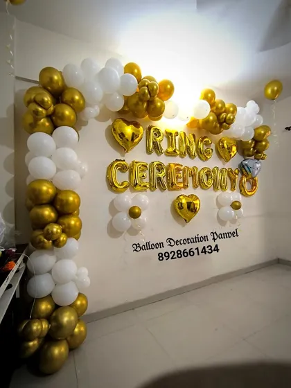 A simple and elegant 'Ring Ceremony' decoration. The gold and white balloon arch with heart-shaped foil balloons is a classic choice for engagement parties.