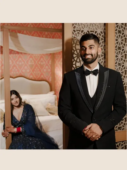 A playful moment between the bride and groom at their reception. Her peeking from behind a four-poster bed while he waits adds a touch of fun and anticipation.
