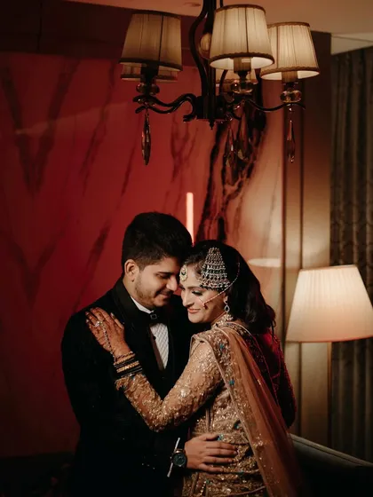 A tender moment between the bride and groom, framed by the warm light of a lamp. Their close embrace and happy expressions make this a deeply romantic shot.
