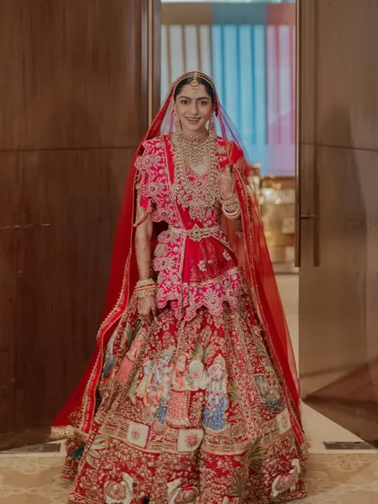 The bride, ready for her new beginning. This full-length shot captures her elegance and the incredible detail of her story-telling lehenga as she steps through a doorway.