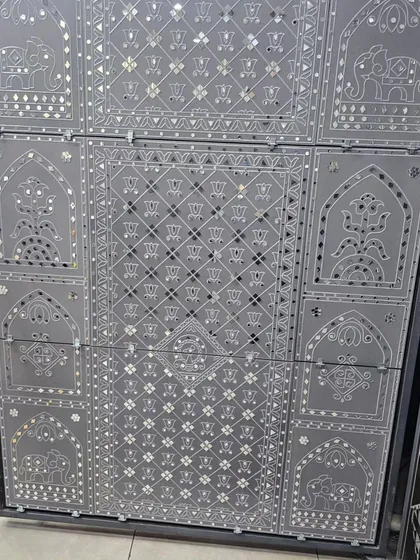 A grey panel featuring intricate Lippan-style mirror work with traditional elephant and floral motifs.